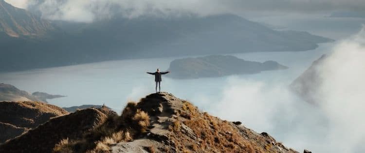 Persona con los brazos abiertos en la cima de una montaña